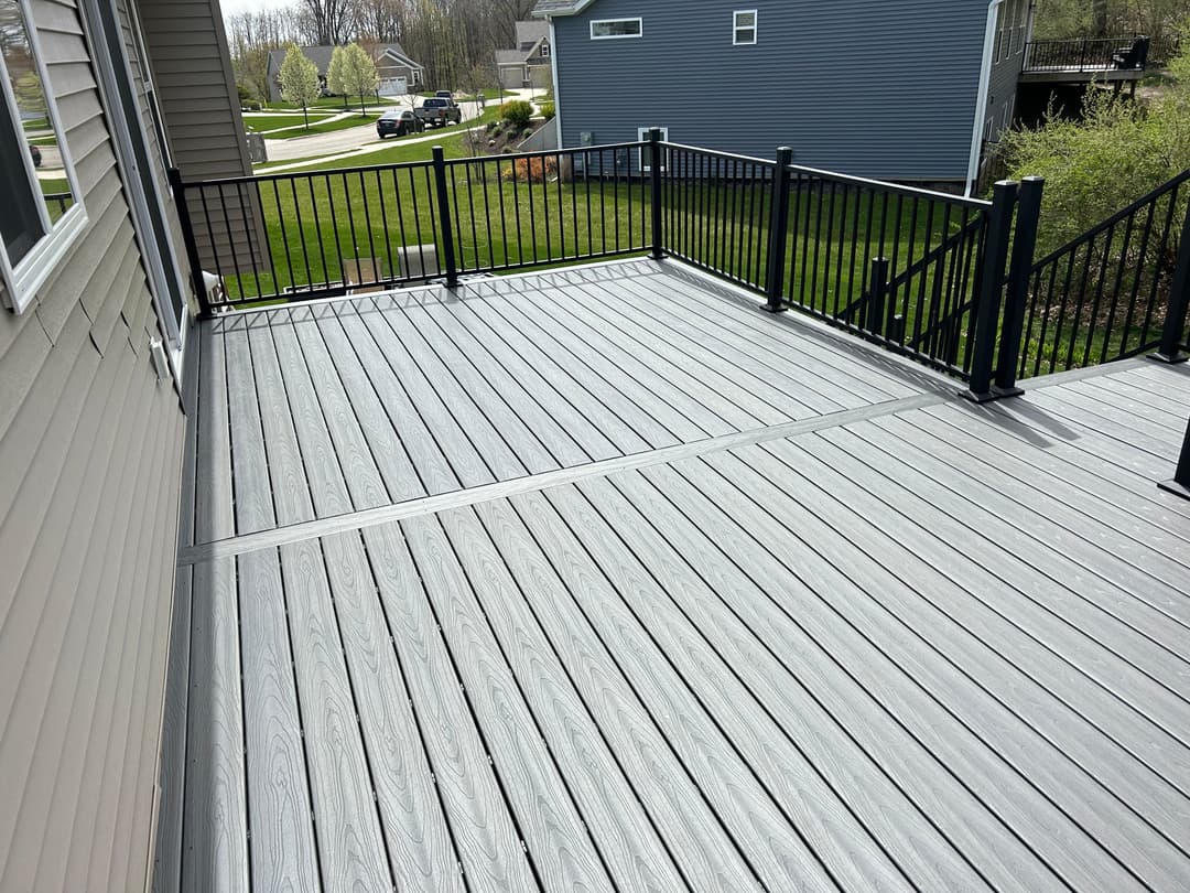 Spacious gray composite deck with black railings and green lawn in the background.