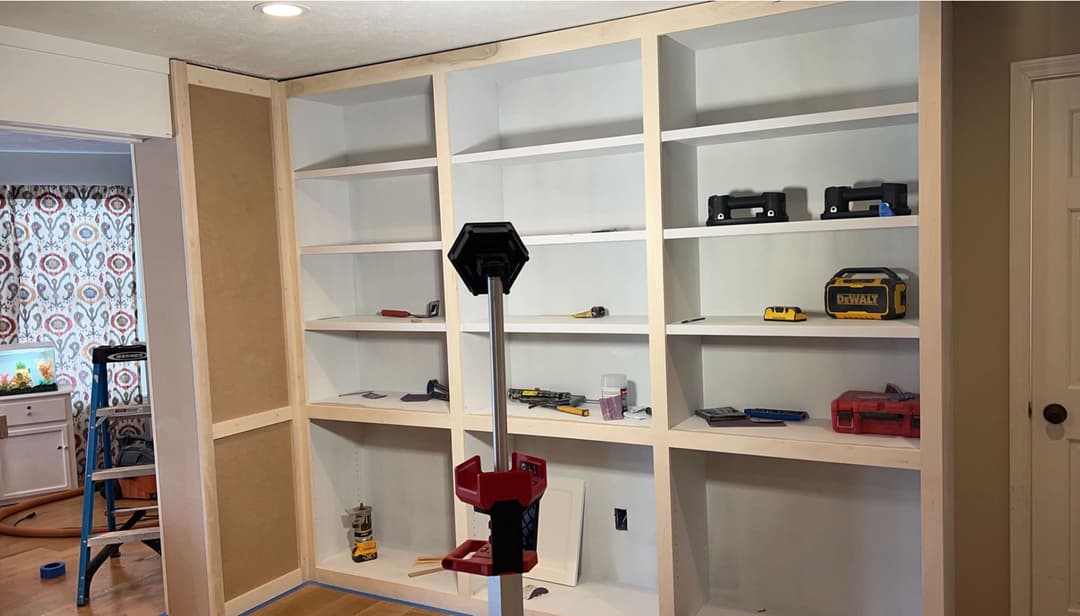 Unfinished custom bookshelf with tools and equipment on a worksite.