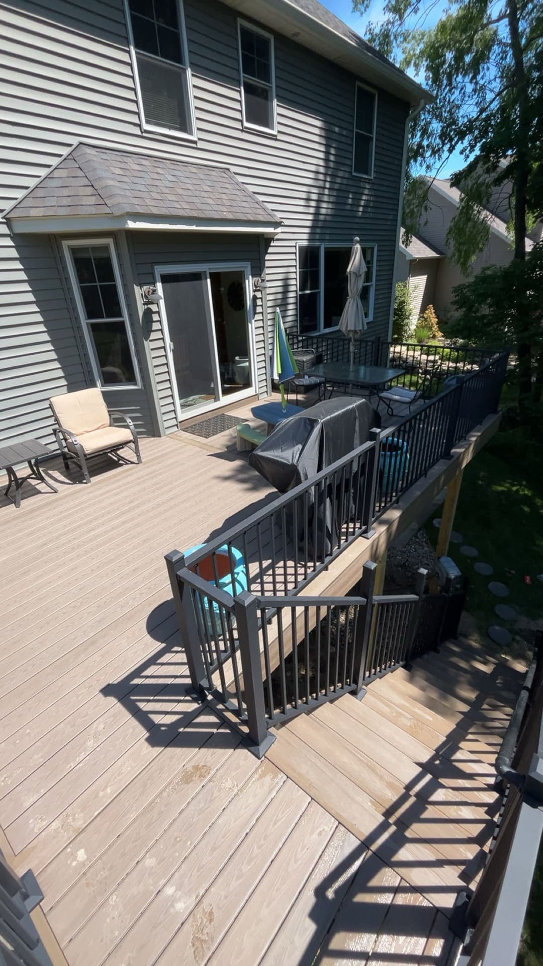 Modern backyard deck with outdoor furniture, grill, and stairs leading to the yard.