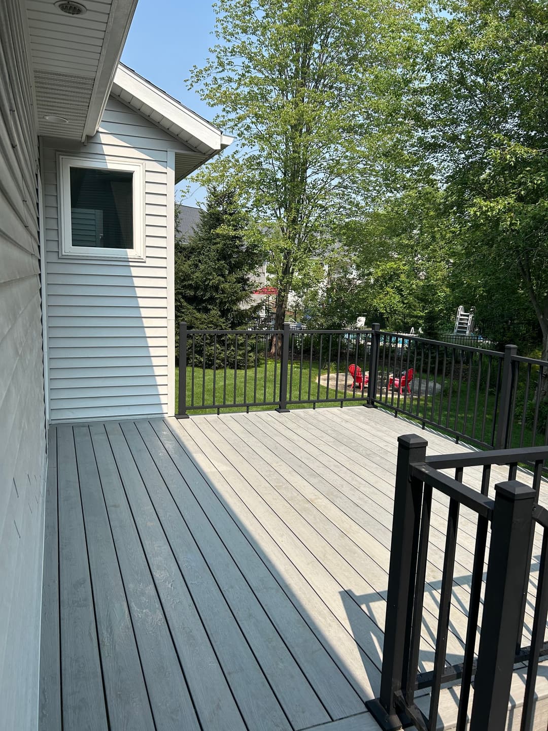 Spacious outdoor deck with black railing and green backyard view, perfect for relaxation.